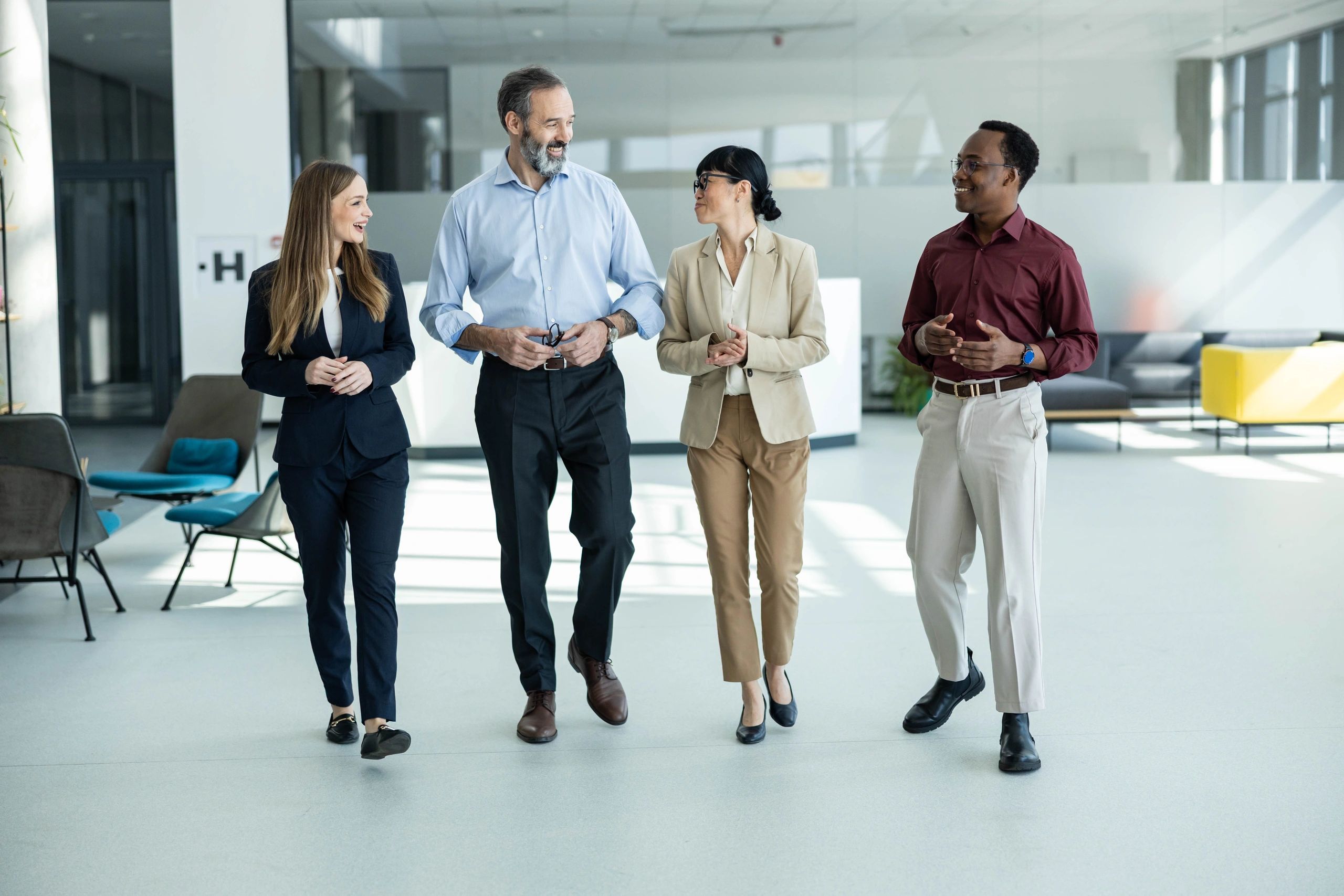 Diverse business professionals walking through a modern office, engaged in discussion and collaboration